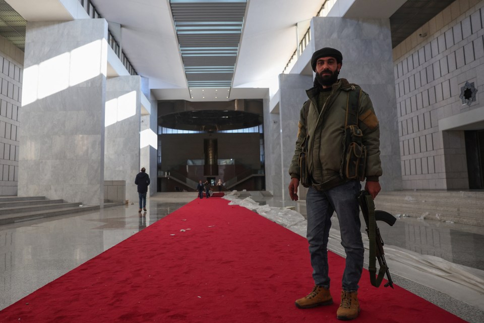 A rebel fighter stands in the Syrian presidential palace in Damascus.