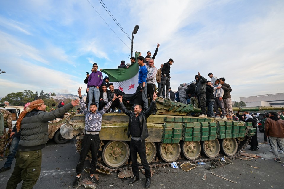 People celebrate with anti-government fighters at Umayyad Square in Damascus on Sunday