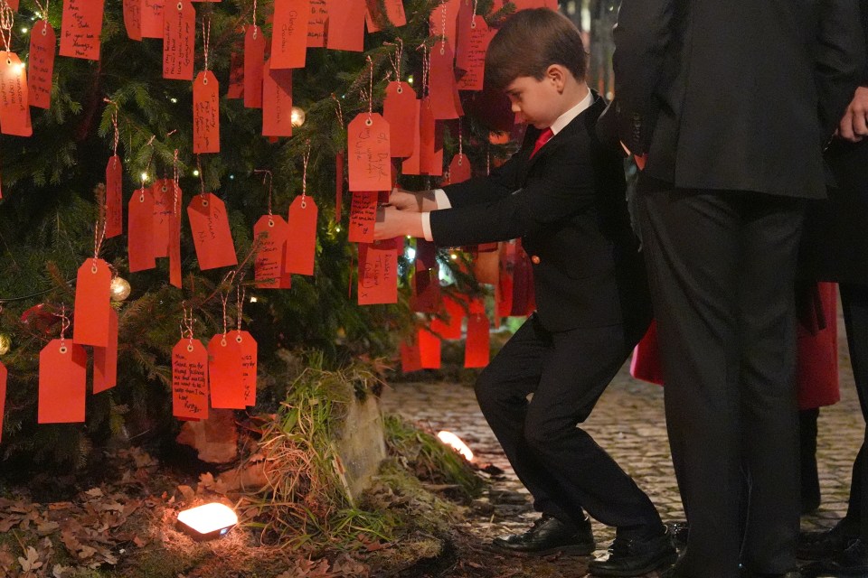 Prince Louis attaching his own red note to the Kindness Tree