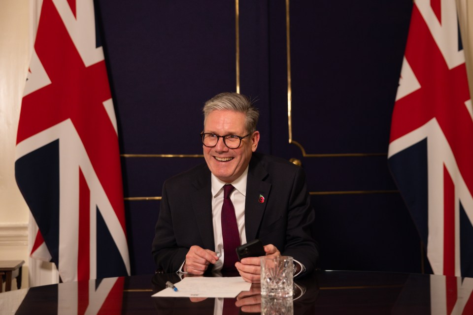 Keir Starmer, UK Prime Minister, smiling while using his mobile phone at 10 Downing Street.