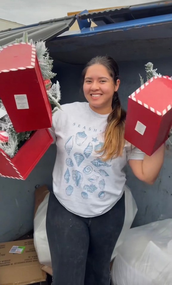 Woman holding discarded Christmas decorations found dumpster diving.