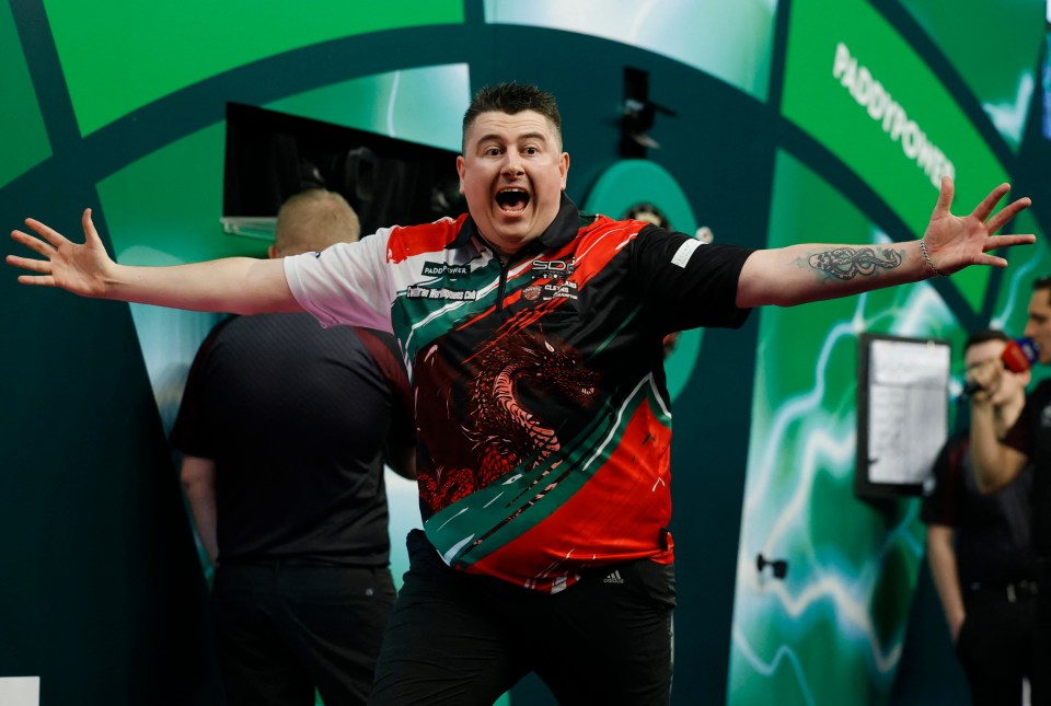 A darts player covers his face with his hands in disappointment.