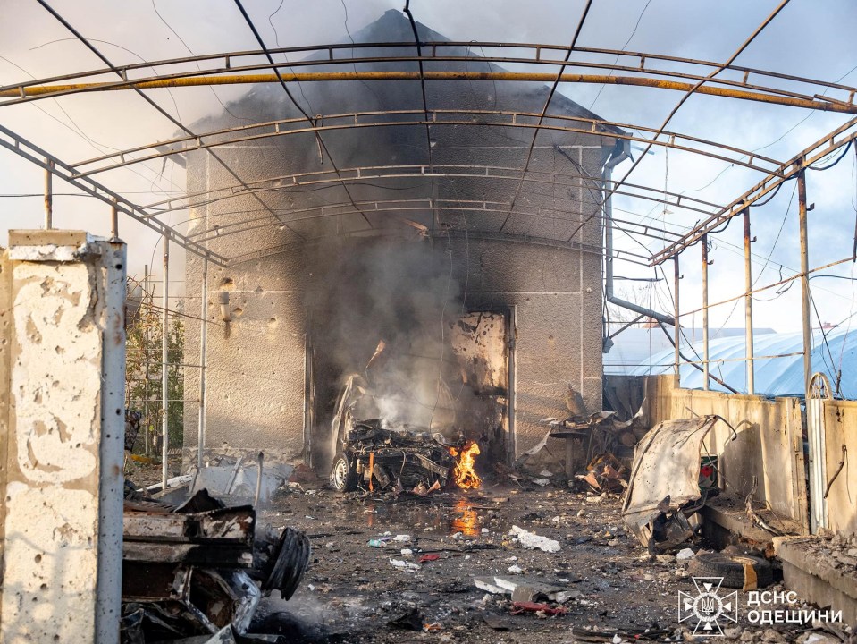 A car burns in the backyard of a residential house after a Russian missile strike