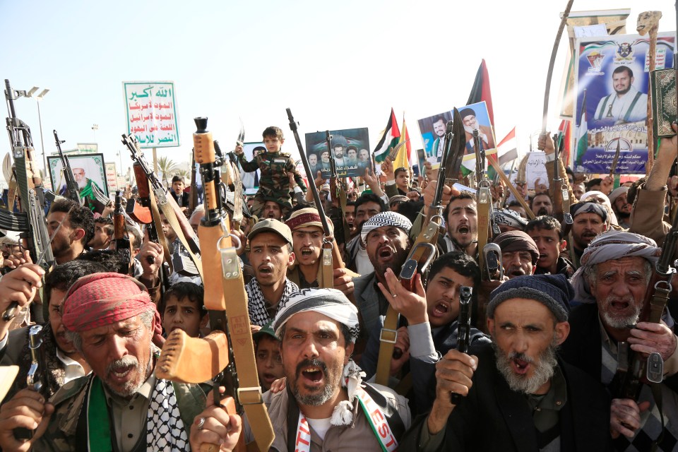 Houthi protesters in Sana'a, Yemen, brandishing weapons and holding signs.