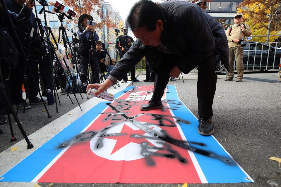 A South Korean protester spray paints on a North Korean flag during an anti-North Korea rally before opposition Leader Lee Jae-myung faces court on election law violation charges