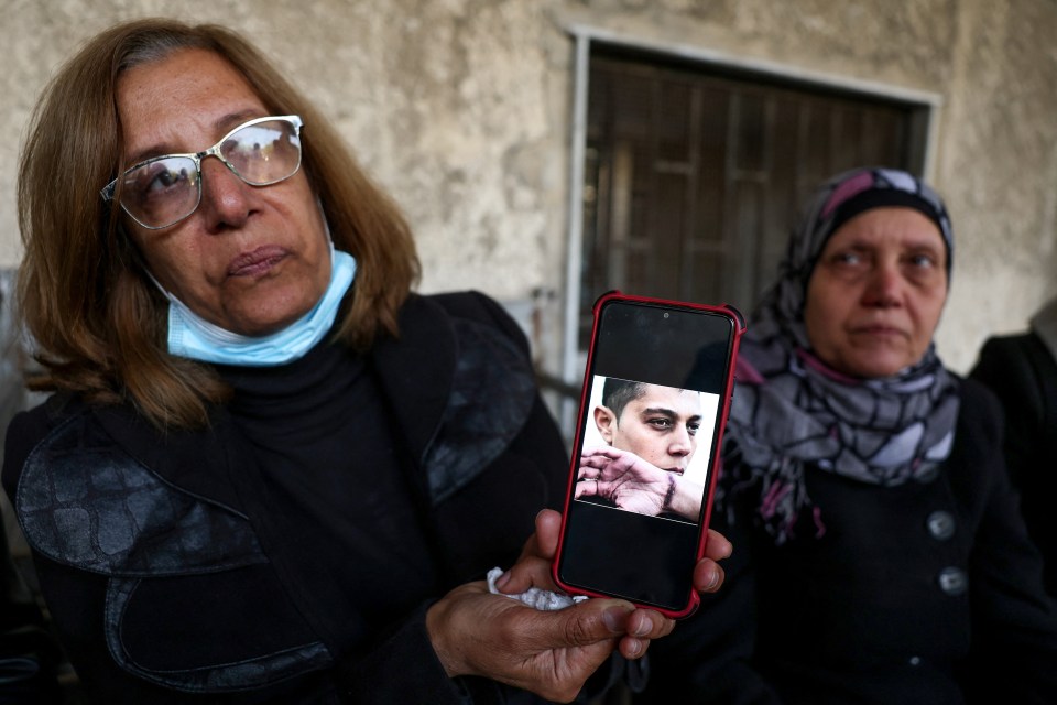 A woman shows the photograph of a missing relative as people come to search for news of loved ones at the morgue of a hospital in Damascus