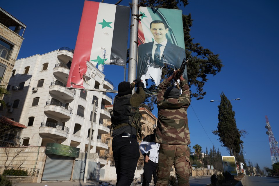 Syrian rebels tear down a portrait of Syrian President Bashar al-Assad in central Aleppo