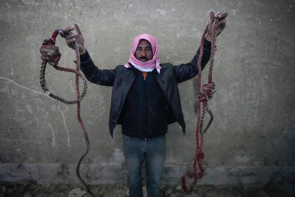 A man holds up two ropes tied into nooses in the infamous Saydnaya military prison