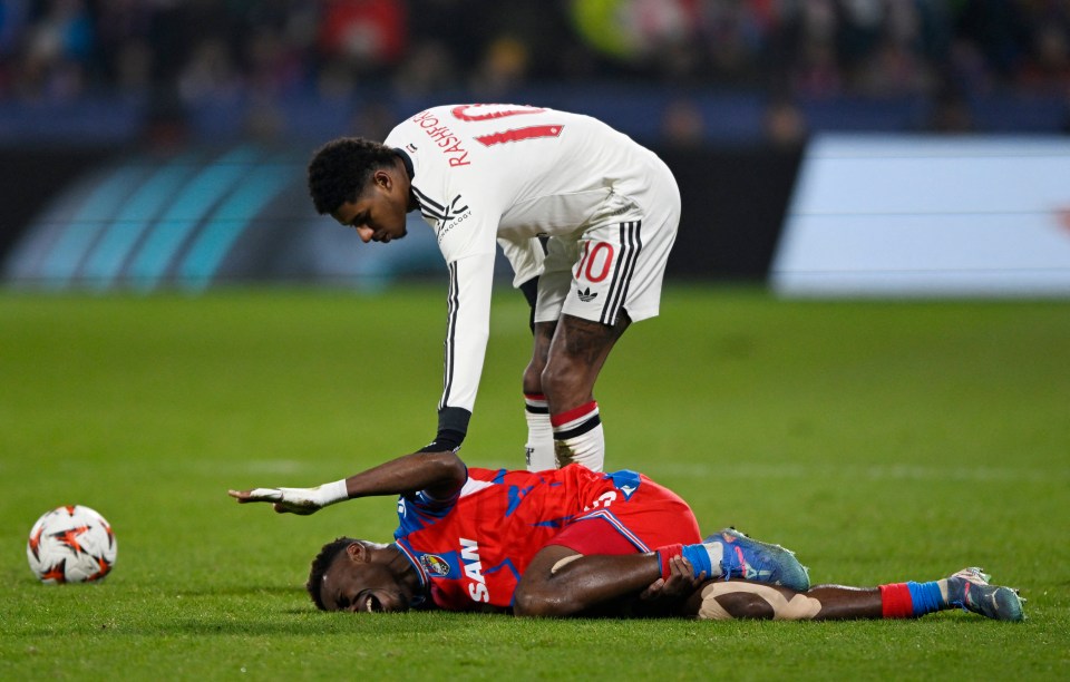 Injured Viktoria Plzen player on the ground attended to by an opponent.