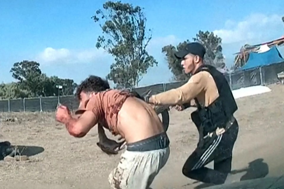 An armed Hamas thug drags an innocent Israeli away from his home on October 7