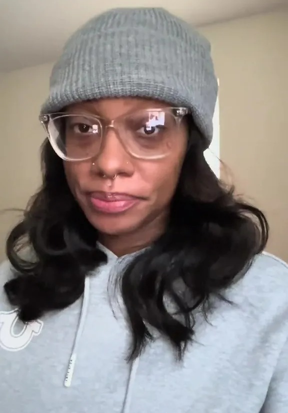 Woman wearing a gray beanie and clear glasses.