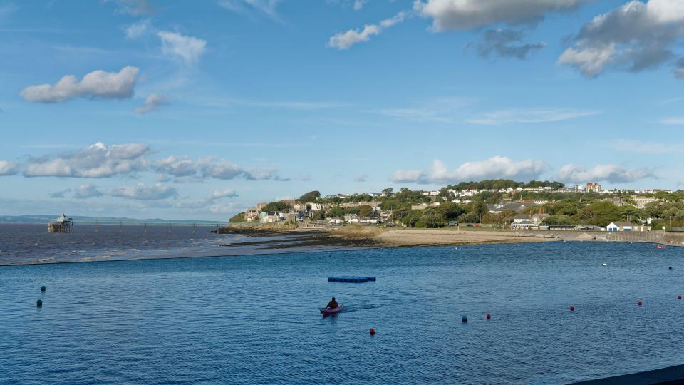 Kayaker in Clevedon Marine Lake, with the town and pier in the background.