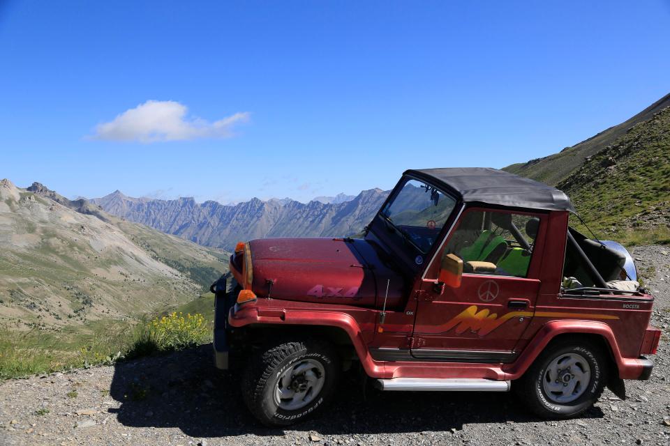 Red Rocsta 4x4 vehicle parked on a mountain pass overlooking a valley.