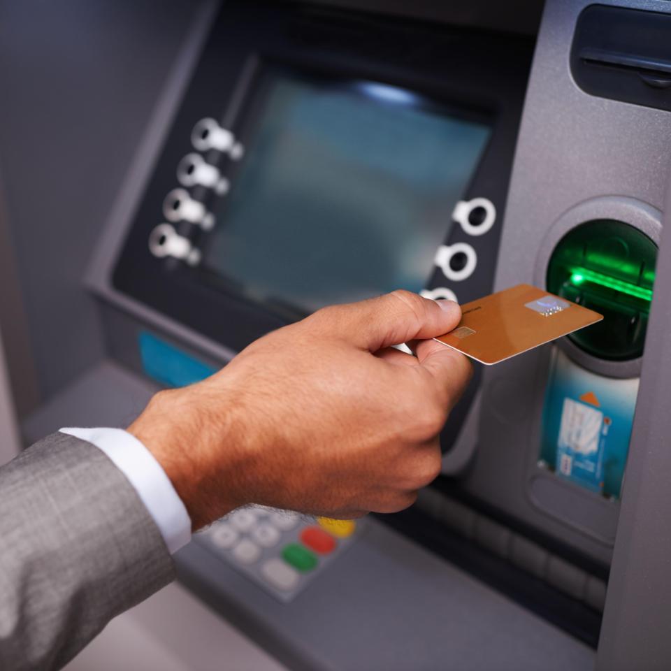 A businessman using his bank card at an ATM.