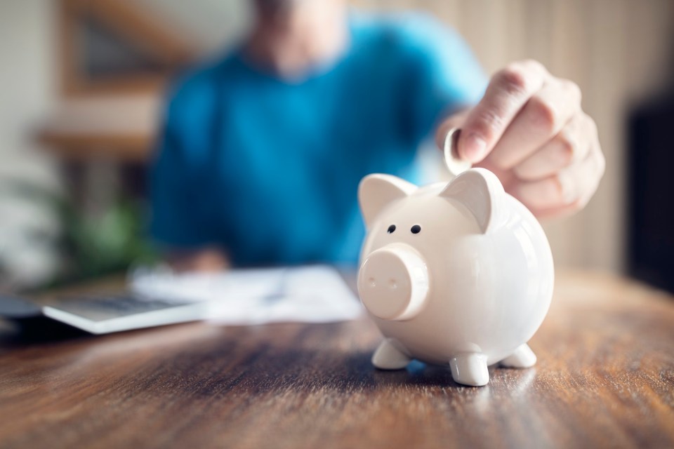 Person putting a coin in a piggy bank.