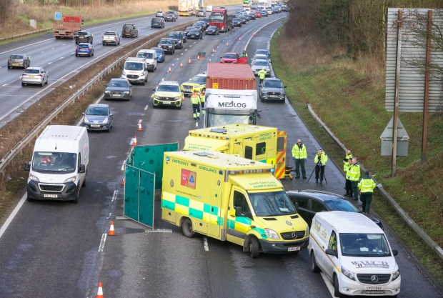 M25 motorway crash scene with emergency vehicles and traffic congestion.