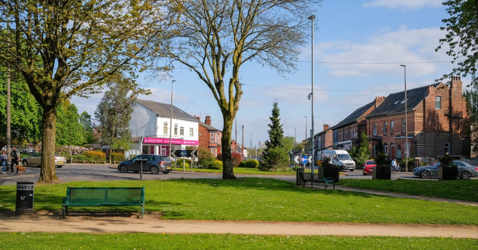 Monton village green with footpaths, seating, and nearby buildings.