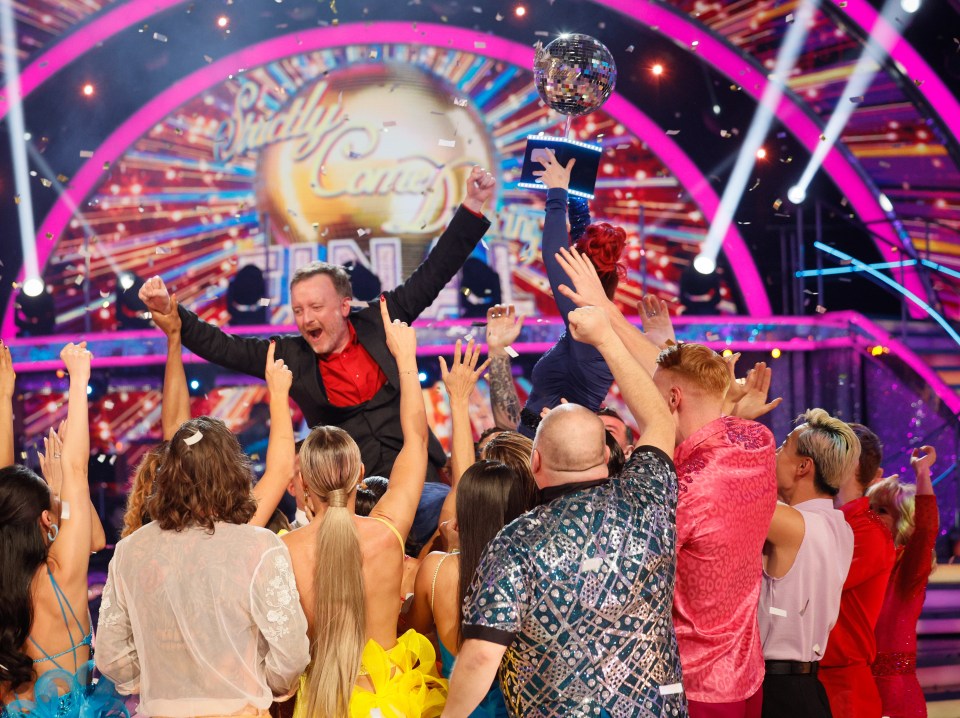 Chris holds the Strictly Come Dancing trophy aloft, surrounded by celebrating dancers.