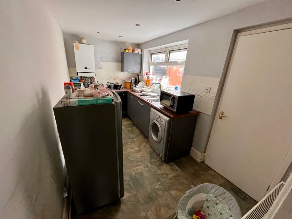 Small kitchen with appliances and baby bouncer.