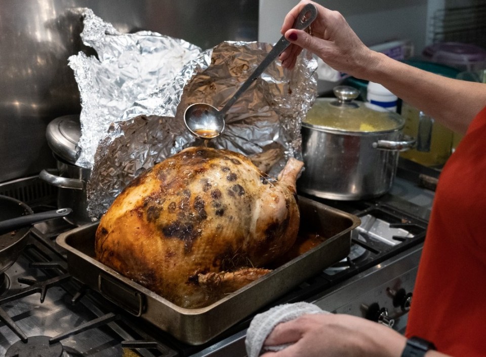 Woman basting a roast turkey.