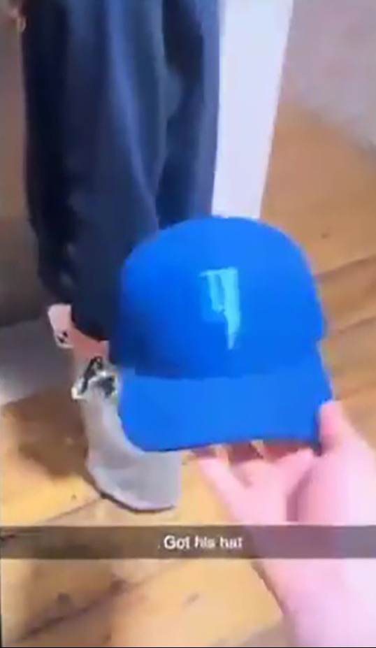 A man holds a blue baseball cap and says 'this is the hat that he wears all the time'