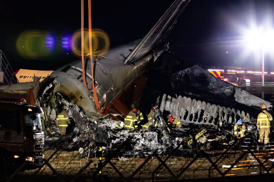 Rescue teams work on the burnt out wreckage