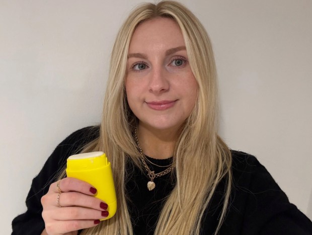 Woman holding yellow deodorant stick.