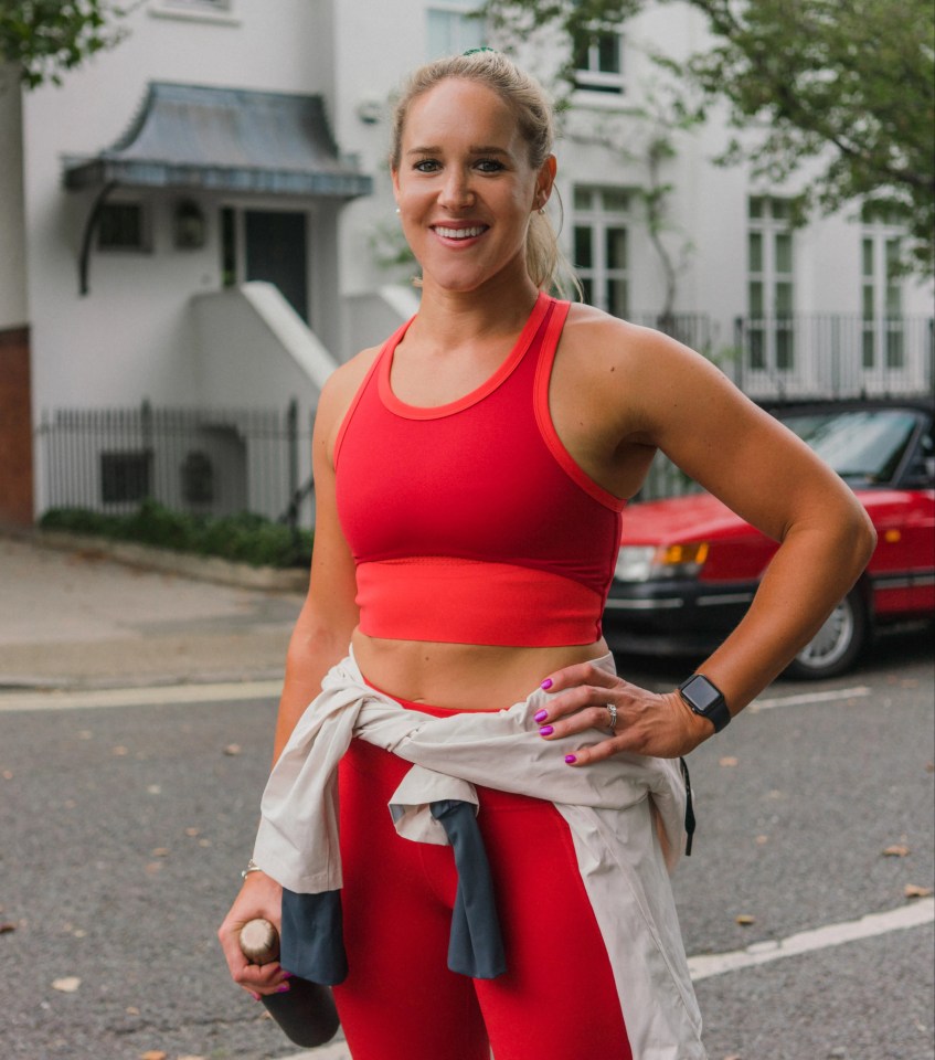 Woman in red athletic wear smiling outdoors.