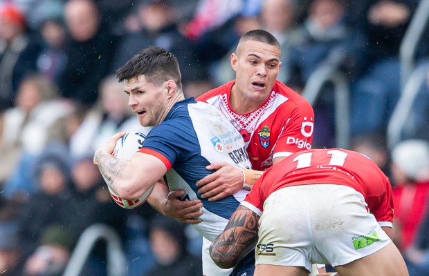 England's John Bateman tackled by Tonga's Tui Lolohea during a rugby league match.