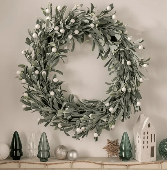 Mistletoe wreath with white berries, displayed with miniature Christmas trees and ornaments.