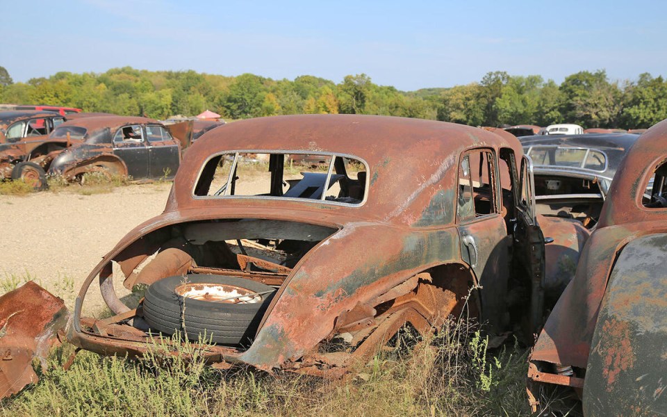 Rusty Cadillac in a junkyard.