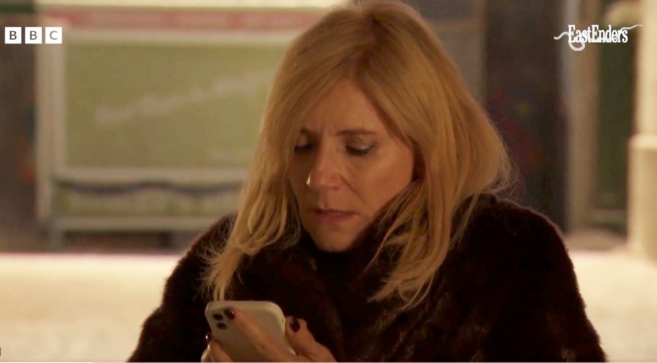 Cindy Beale on her phone in an EastEnders scene.