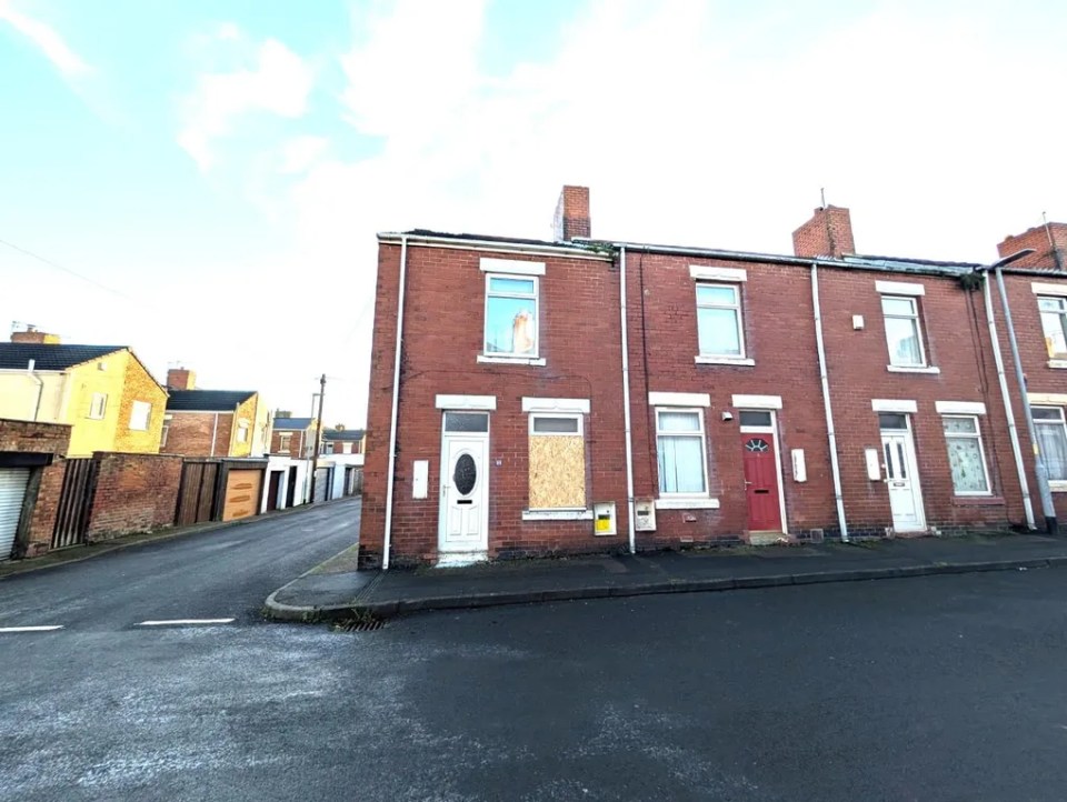 House 80, a terraced house with boarded-up windows.