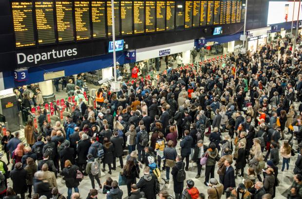 Crowded Waterloo Station during rush hour with delayed trains.