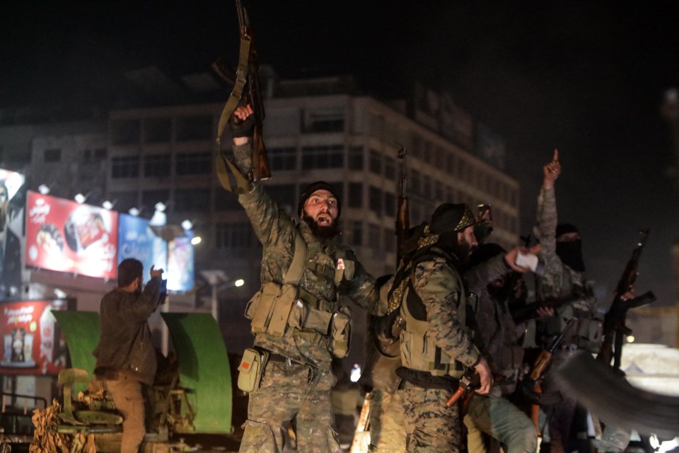 Rebel fighters celebrate as they take the Syrian city of Hama