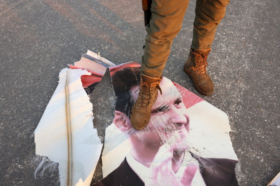 An anti-government fighter steps on a torn up portrait of Syria's President Bashar al-Assad in Hama