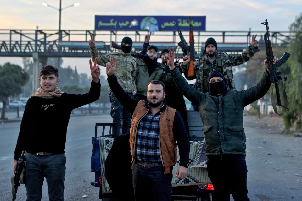 Syrian rebel fighters celebrate the victory at the entrance of Homs