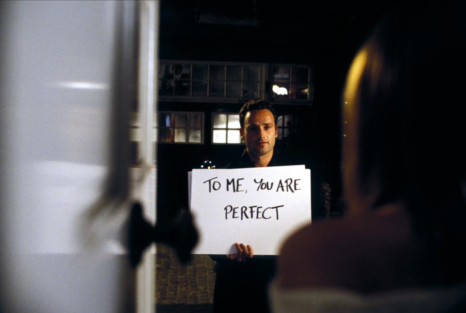 Man holding a sign that says "To me, you are perfect" in Love Actually.