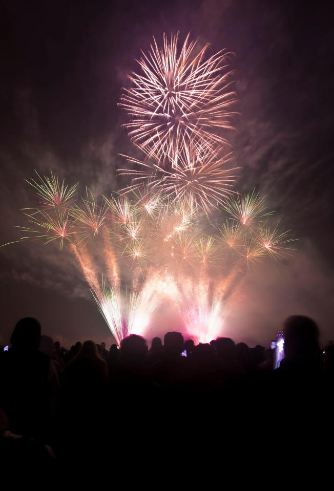 Fireworks display over a crowd of people.