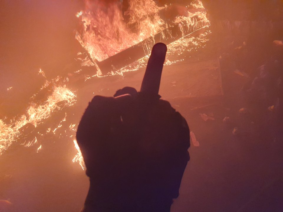 Rebels give the burning coffin a middle finger