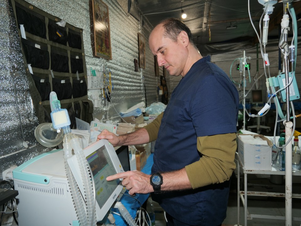 A doctor operates a ventilator in a makeshift medical facility.