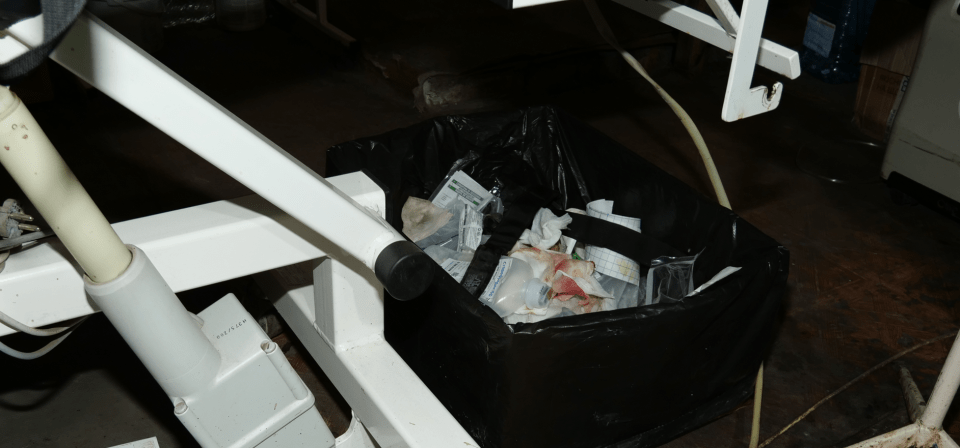 Medical waste in a black bag under a medical device.