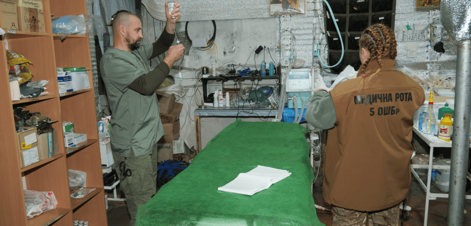 Two medics in a makeshift medical facility prepare medical supplies.