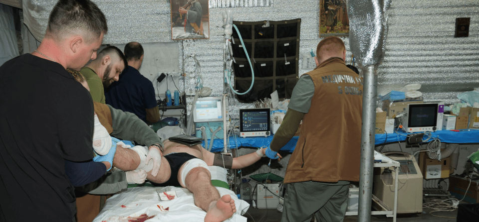 Medics treating a wounded soldier in a field hospital.