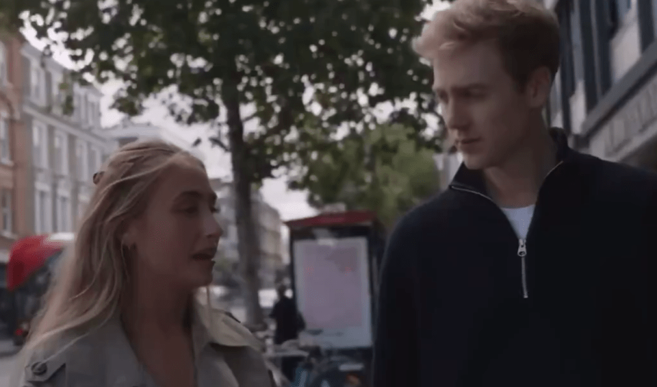 A young woman and man talking on a city street.