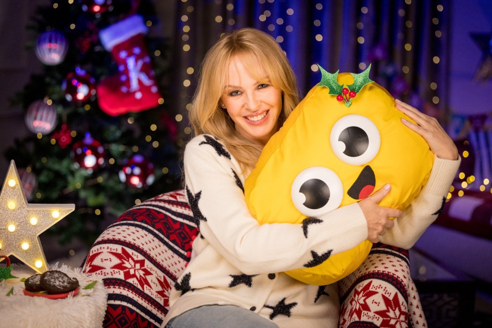 Woman in a Christmas sweater hugging a yellow holiday pillow.