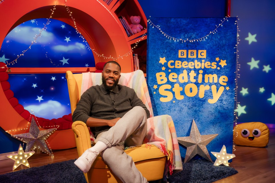 A man sits in a yellow armchair in a set designed for a children's bedtime story.