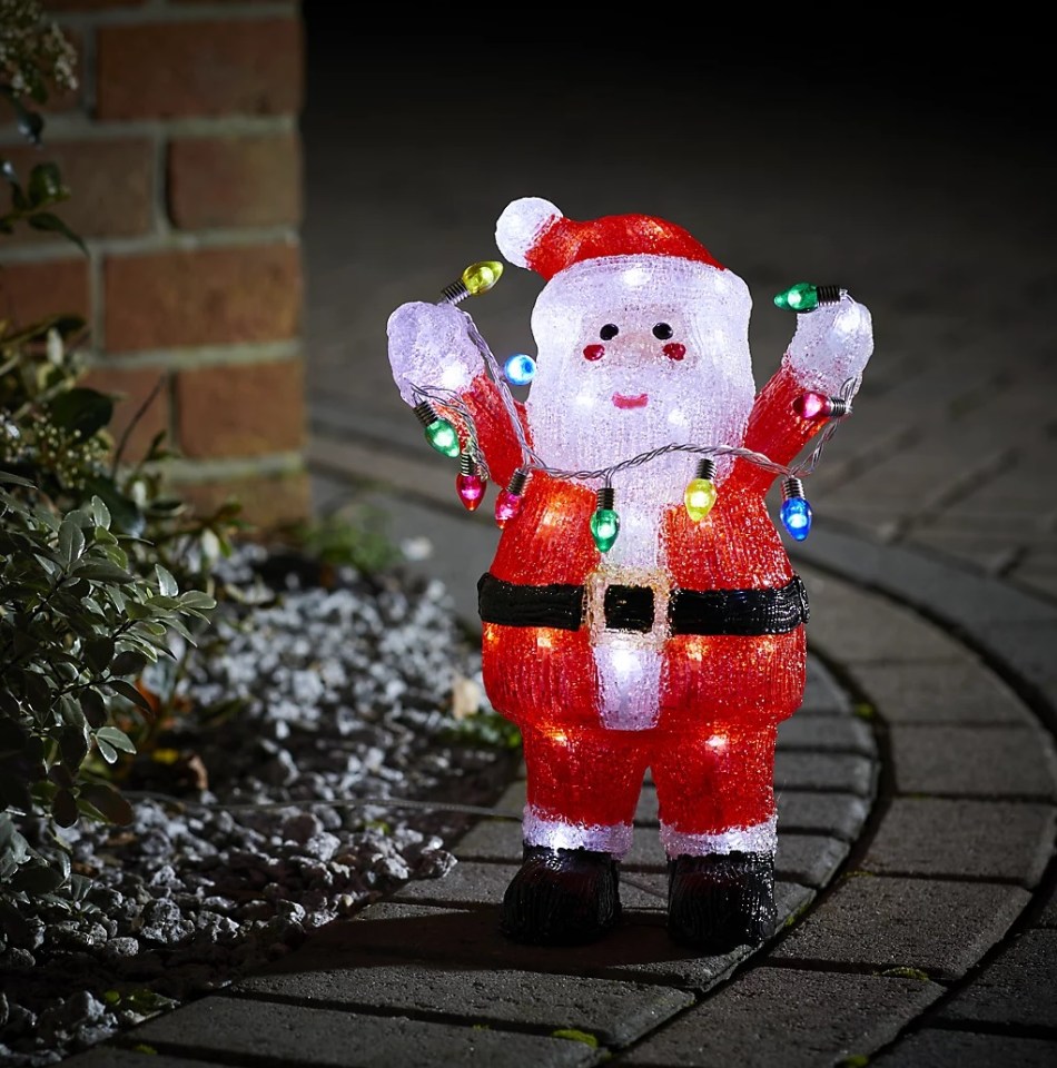 Illuminated Santa Claus holding string lights.