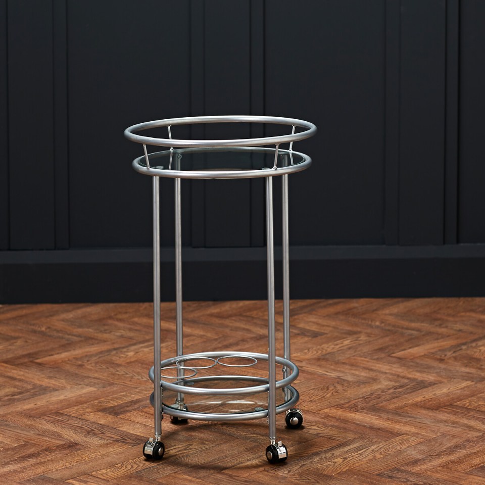 Silver bar cart with glass shelves and wheels.