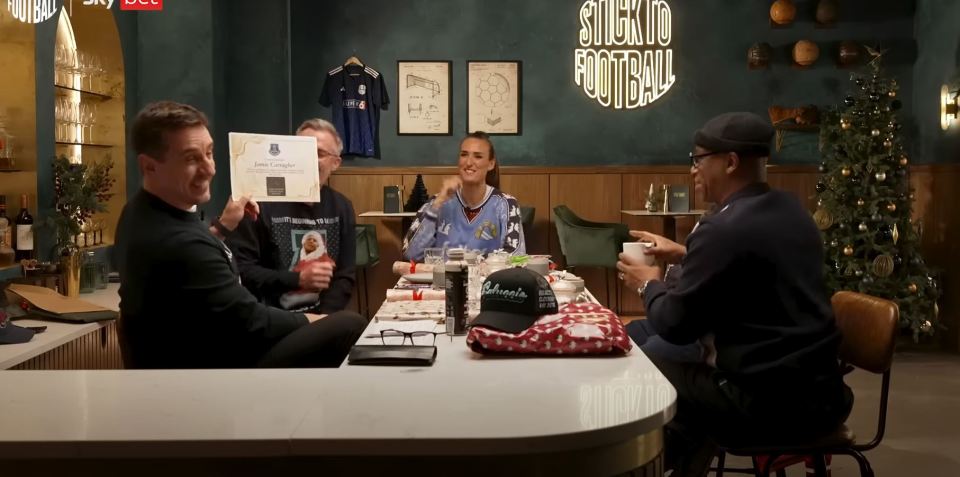 Four people sitting at a table, one holding a certificate for Jamie Carragher.